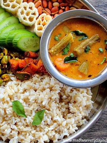 instant pot sambar served with rice, cucumber, veggies and peanuts in a steel plate.
