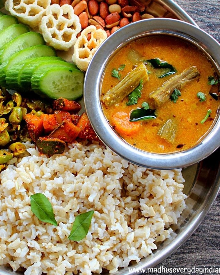 instant pot sambar served with rice, cucumber, veggies and peanuts in a steel plate.