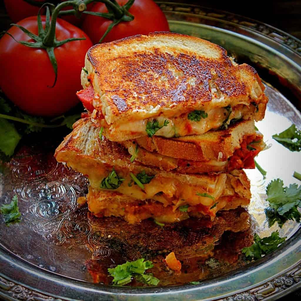 stacked tomato chutney grilled cheese in a metal plate