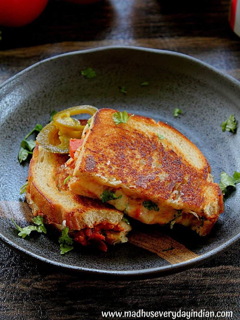 2 slices of the chutney grilled cheese served in a black plate garnished with cilantro