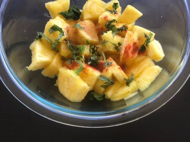 pineapple pieces, chaat masala, chili powder and mint added in a  bowl