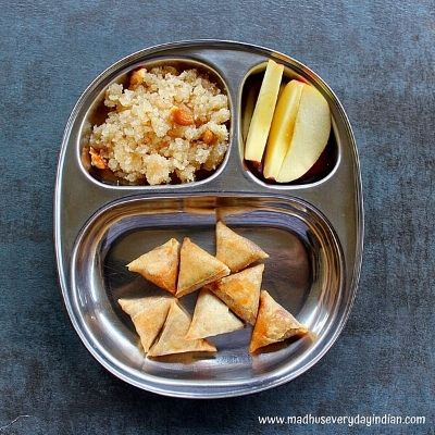 mini samosa, halwa and apple slices served in a steel plate