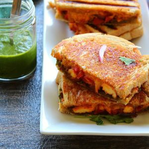 3 paneer sandwiches stacked on each other and served with green chutney
