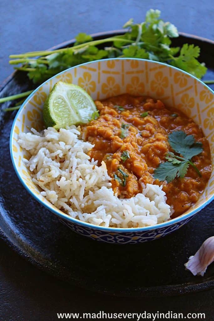 red lentil curry with coocnut and cashew cream served ina  bowl with cumin rice and lime