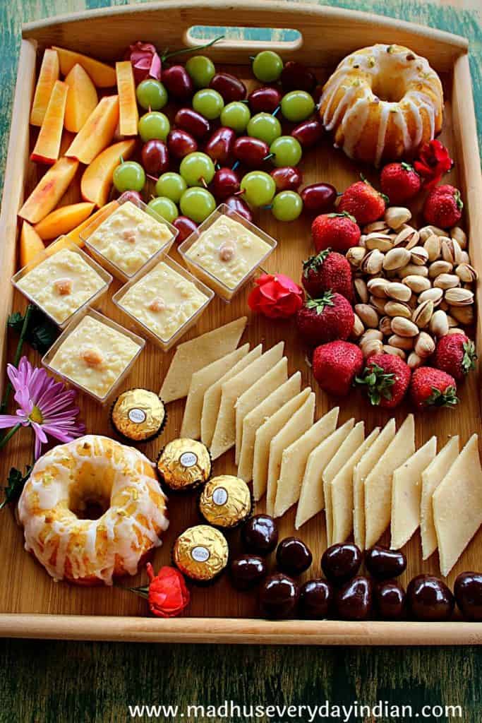 indian dessert charcuterie board with assorted sweets, cake, nuts and fruit