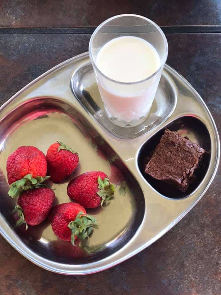 strawberry, milk and brownie served in a steel plate