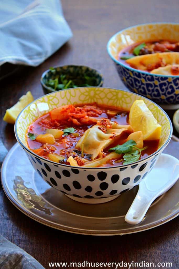 asian vegetable soup with dumpling served in a large bowl garnished with cilantro and lime