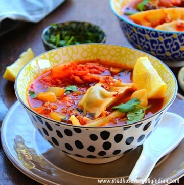 asian vegetable soup with dumpling served in a large bowl garnished with cilantro and lime