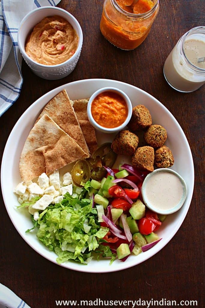 pita, falafel, sauce and salad served in a large plate