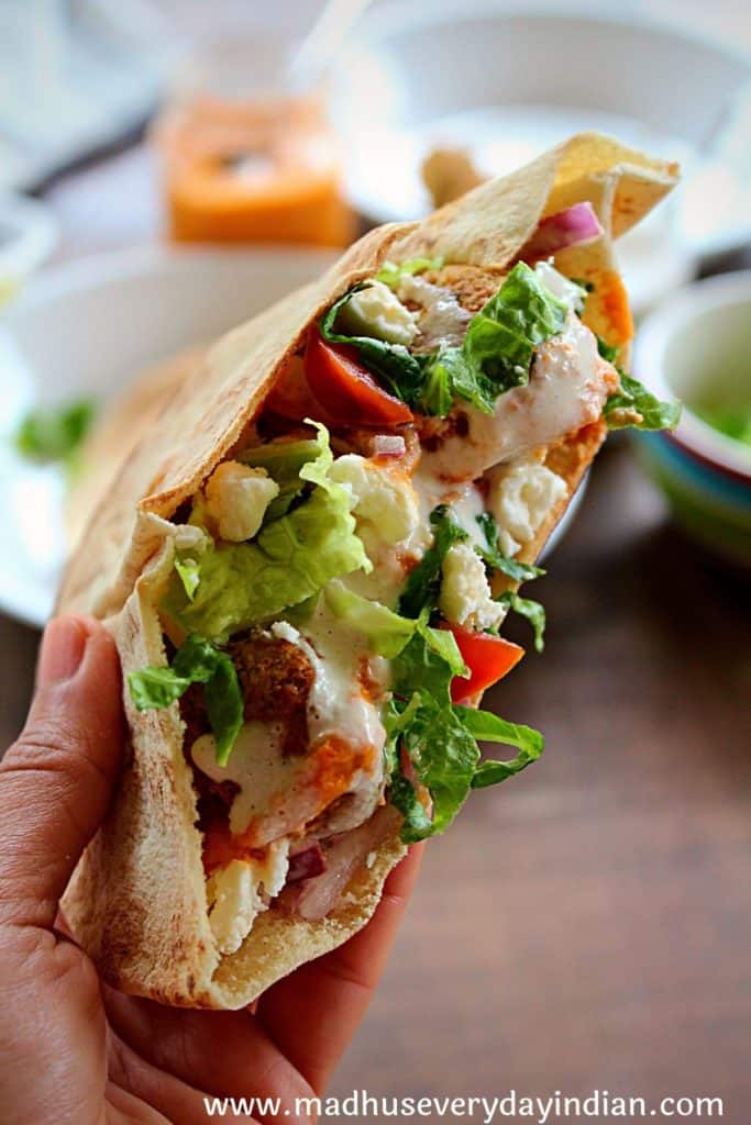a hand holding the falafel pita sandwich