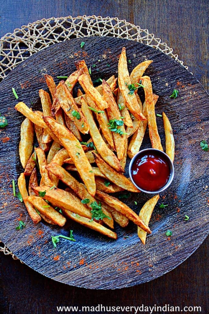 masala french fries served in a brown plate with ketchup