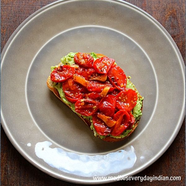 avocado toast served on a sour dough bread topped with roasted cherry tomato