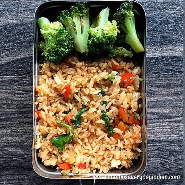 fried rice and broccoli served in a steel lunch box
