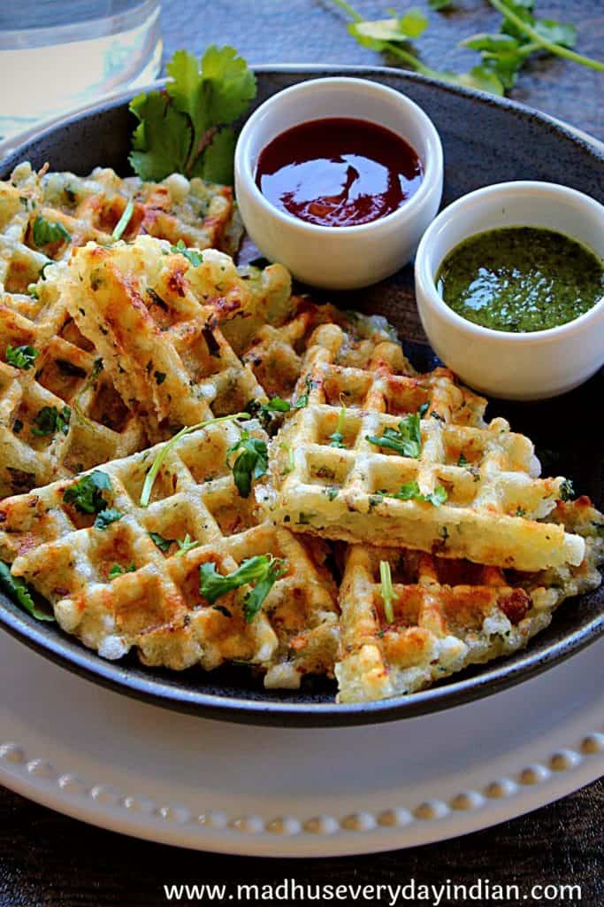 sabudana waffles erved in a black plate with 2 sauces