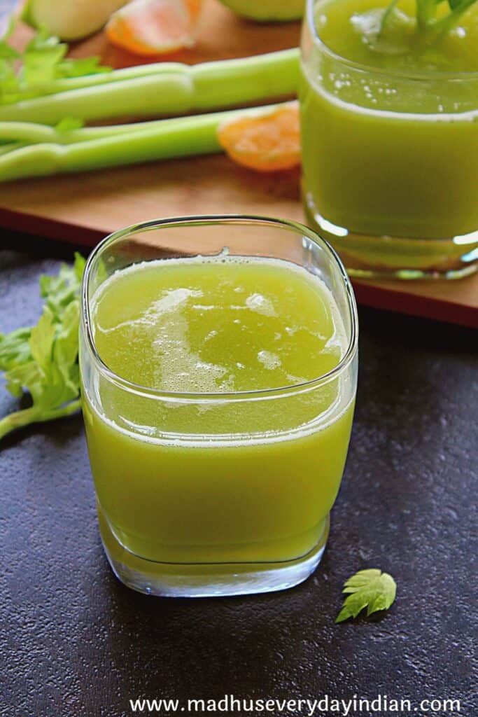 celery apple and orange juice served in a glass cup