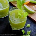 celery juice served in a glass cup with celery leaves