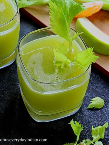 celery juice served in a glass cup with celery leaves