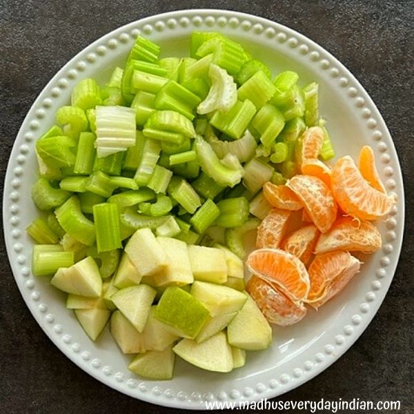 celery, orange and apple chopped and placed in a white plate