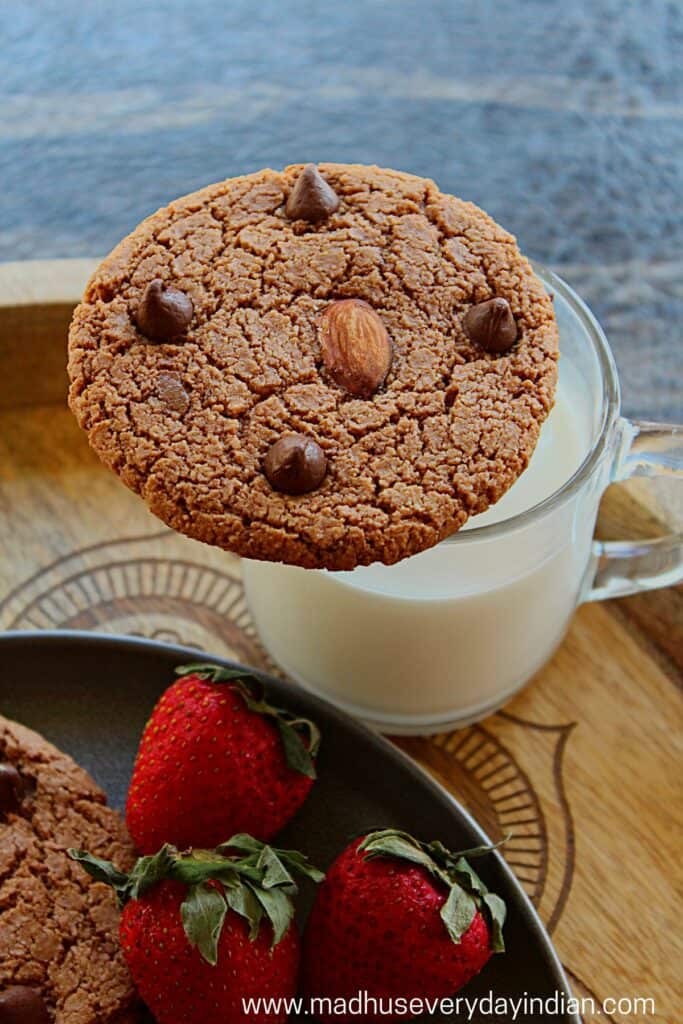 chocolate almond cookies placed on top of a cup of milk