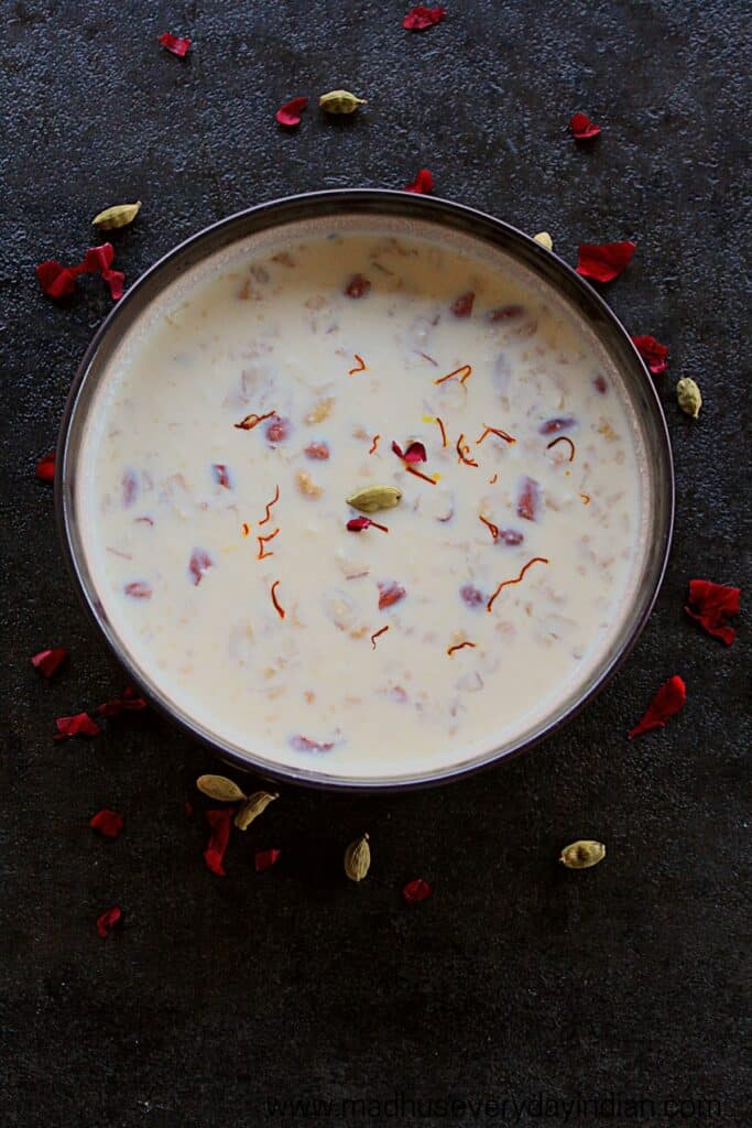 rabdi served ina  large bowl garnished with rose petals, saffron and cardamom