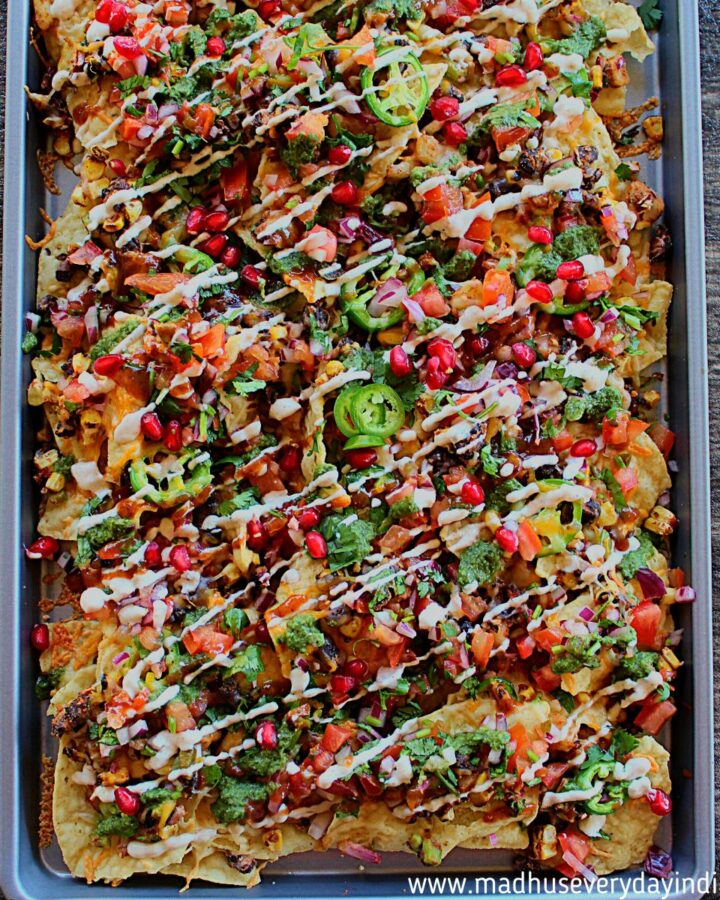 tortilla chips topped with bean mixture, cheese and chutneys served in a baking tray