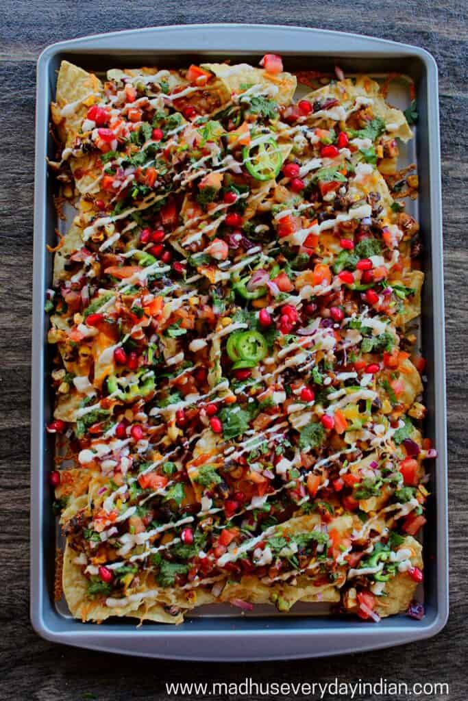 tortilla chips topped with bean mixture, cheese and chutneys served in a baking tray