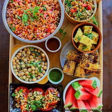 different varieties of food is arranged in different bowls in a big wooden board
