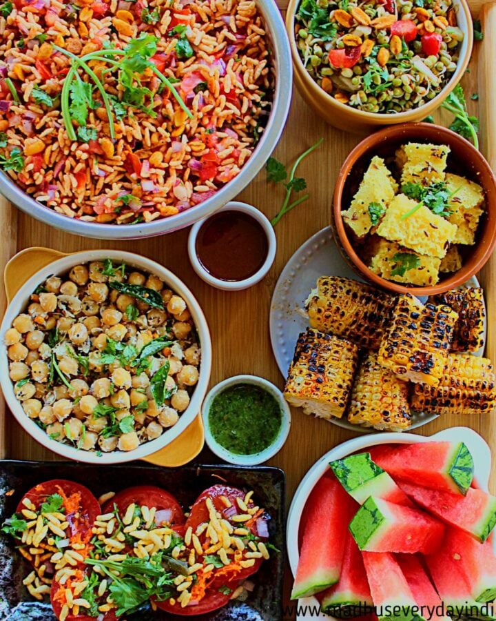 different varieties of food is arranged in different bowls in a big wooden board