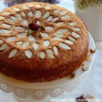 almond cake arranged in a cake tray with dry rose petals and cardamom pods