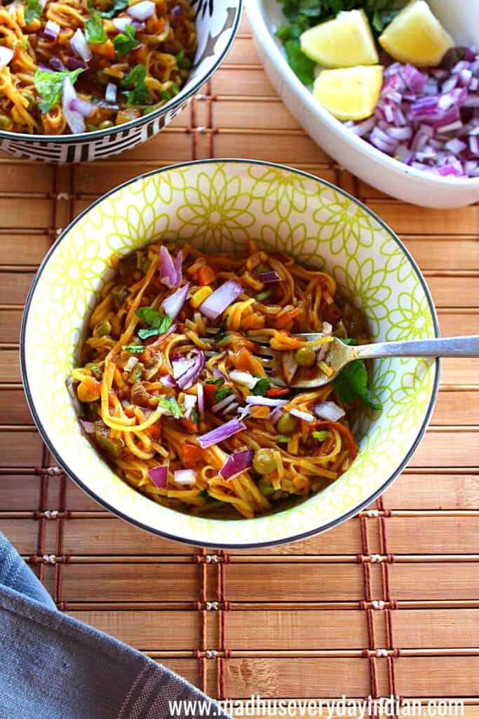 pav bhaji noodles served in a bowl topped with chopped red onion