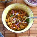 pav bhaji noodles served in a bowl topped with chopped red onion