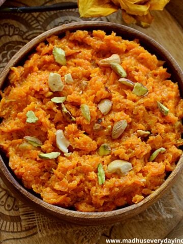 indian carrot pudding served in a wooden bowl topped with nuts