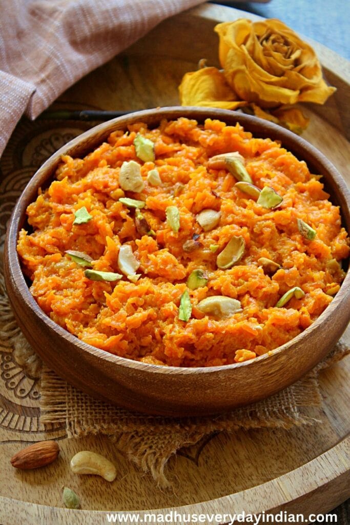 indian carrot pudding served in a wooden bowl topped with nuts