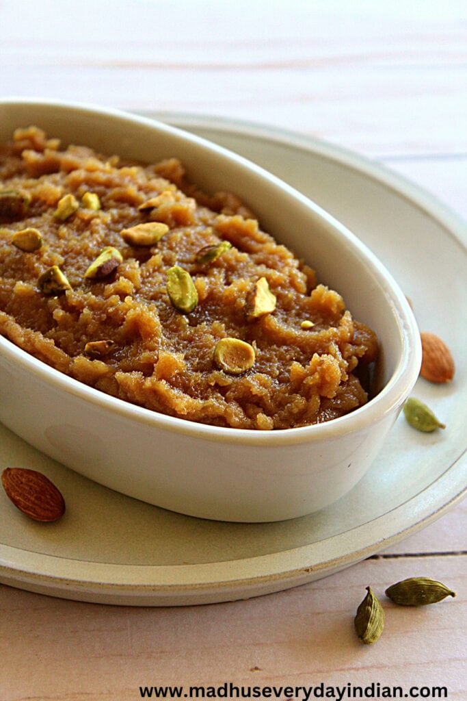 badam halwa served in white oval bowl garnished with pistachio