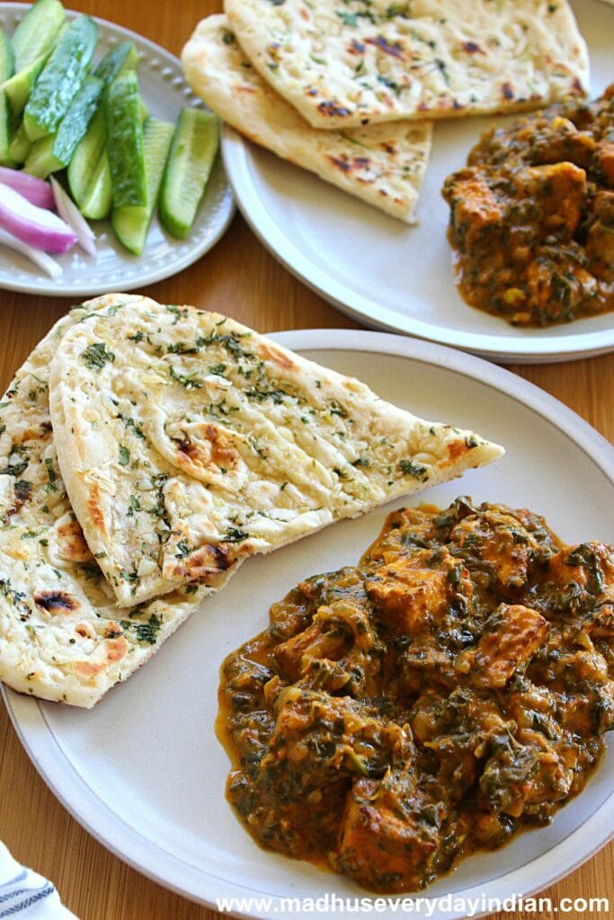 palak tofu tikka masala served with two pieces of naan and cucumber