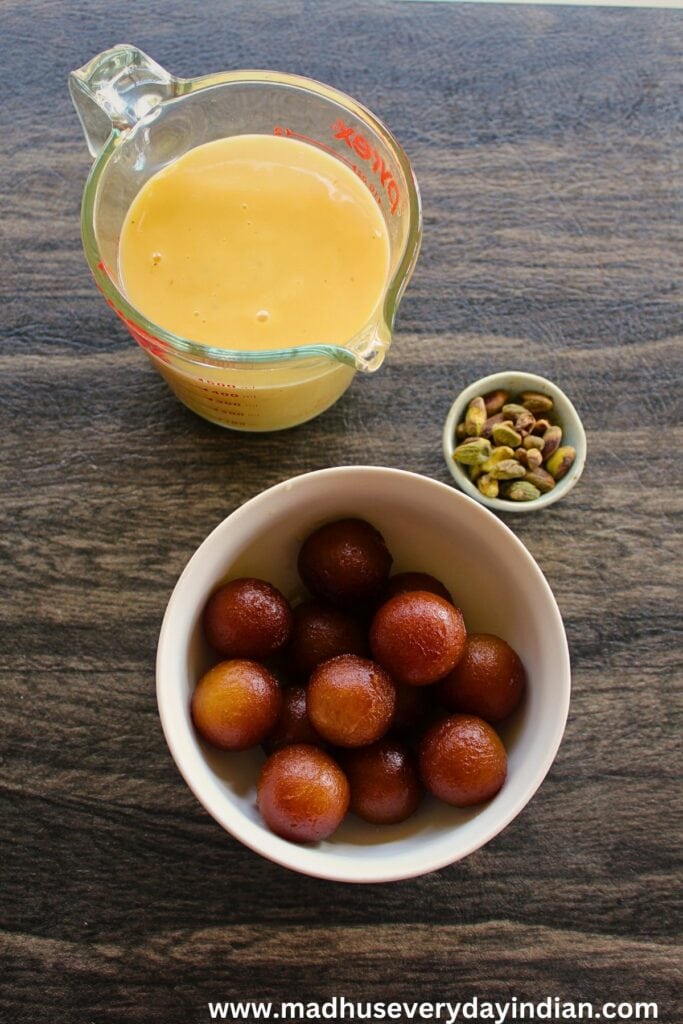 custard, gulab jamun and pistachio in the picture
